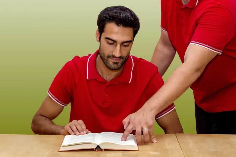 Homme lisant livre avec aide